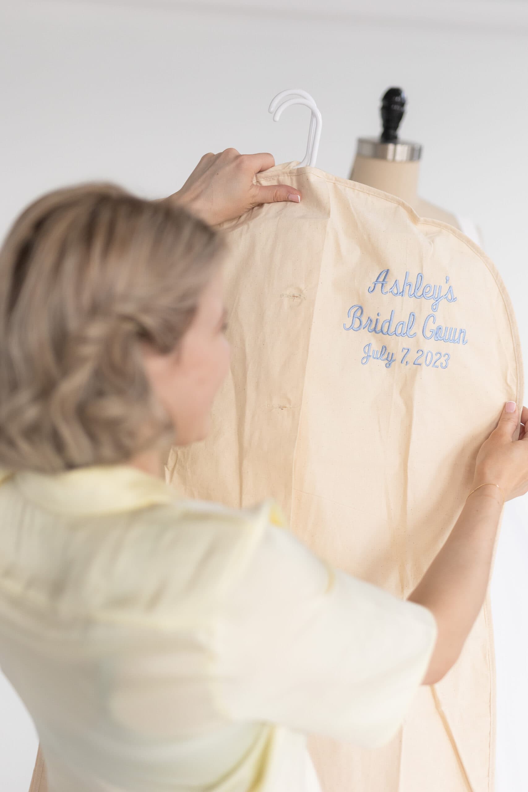 Sarah kolis holding wedding gown in bag for custom couture bride ashley 2023