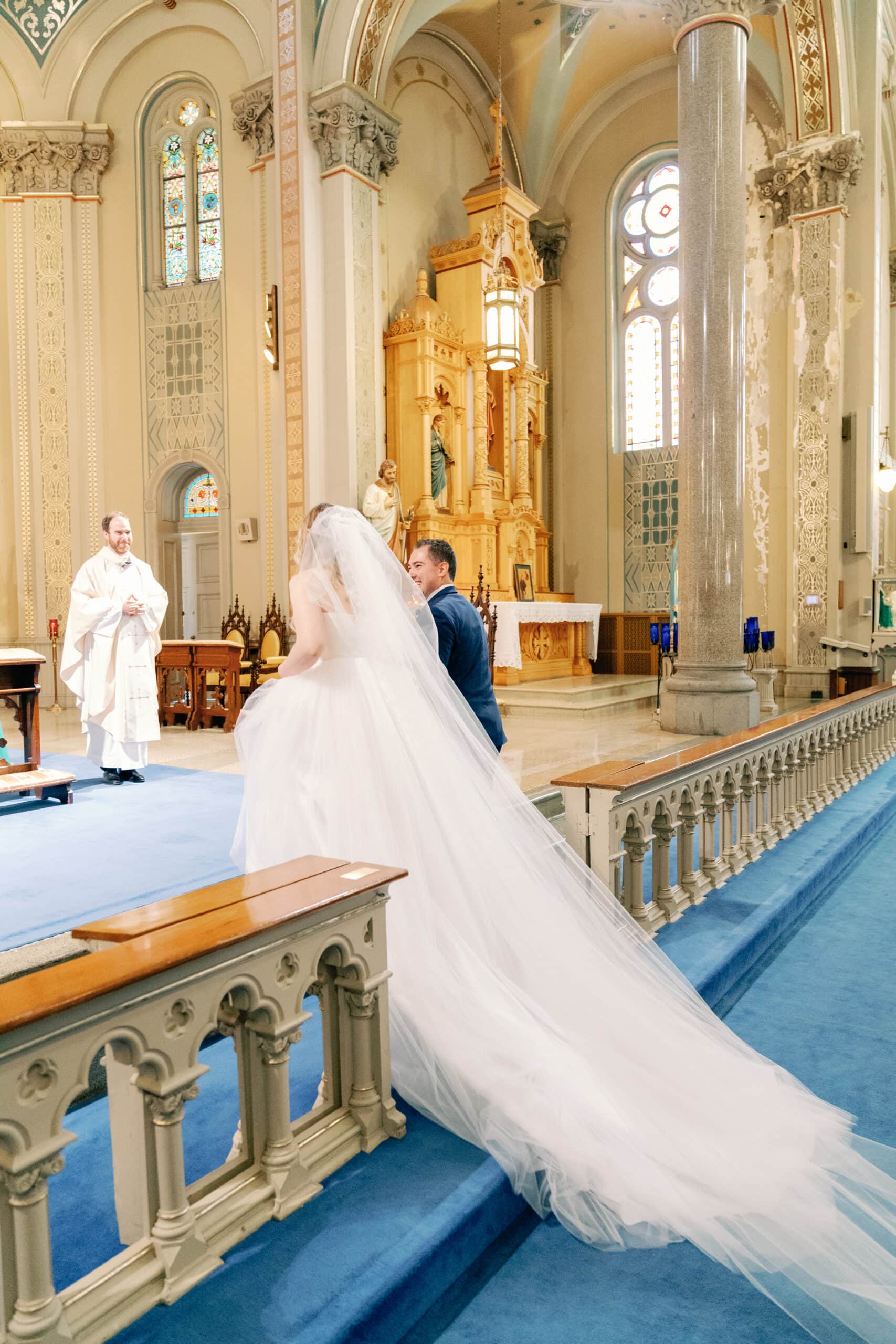 Couture Bride Ashley in Custom Sarah Kolis Gown and veil and groom in cathedral